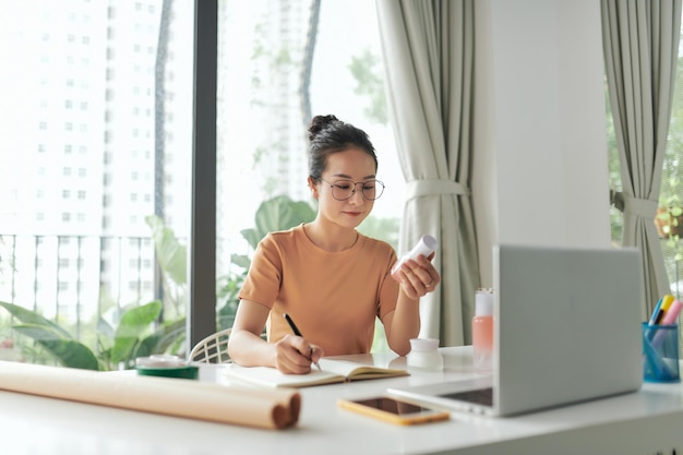 Freelance vrouwelijke verkoper controleert productbestelling om zich voor te bereiden op levering aan klanten