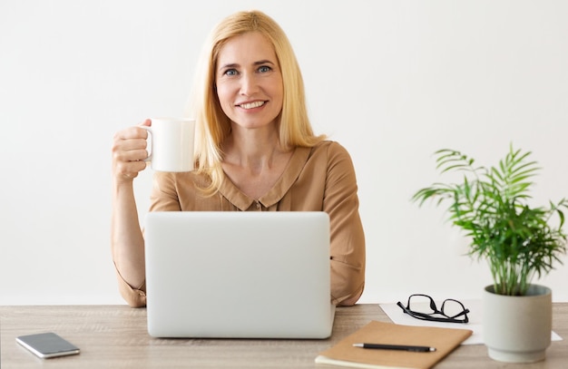 Freelance werk Glimlachende vrouw die werkt en koffie drinkt