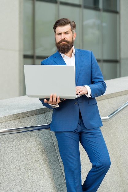 Freelance werknemer in formeel modepak werkt online met behulp van laptopcomputerapparaat moderne technologie stedelijk buitenshuis, freelancen.