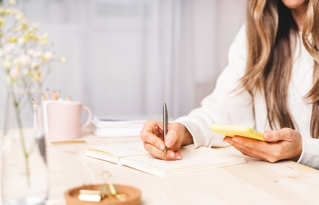 Donna freelance con laptop e tazza di caffè utilizzando il telefono cellulare e lo shopping online, seduto sul divano. ragazza felice che woking dal ministero degli interni. formazione a distanza in linea, istruzione e lavoro.