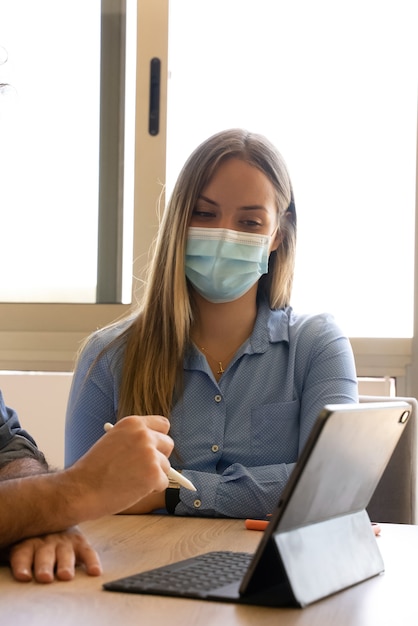 freelance woman with a mask attends to the laptop at the meeting