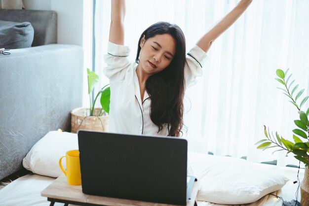 Freelance woman working in business by using laptop computer on a bed at home young girl lifestyle