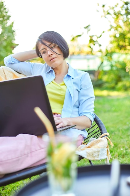 Freelance woman works on laptop at home in the backyard