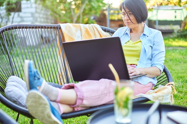 Freelance woman works on laptop at home in the backyard