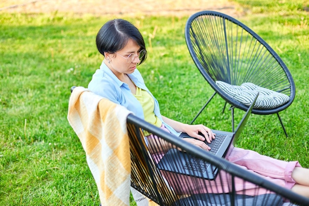 Freelance woman works on laptop at home in the backyard