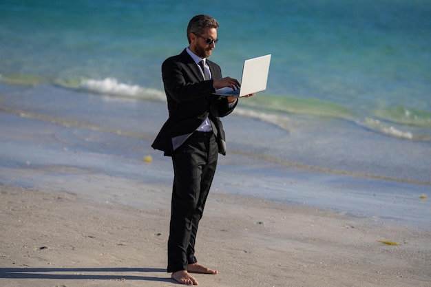 Freelance work online business summer business businessman in suit hold laptop and run on sea funny