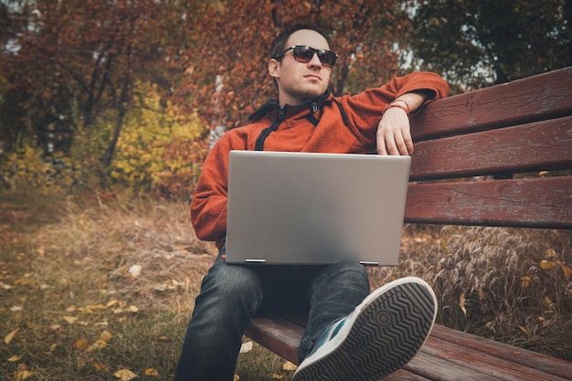 Freelancer in autumn Park Magazine editor revising new article received by email man surfing web on a laptop connected to wifi Student preparing for exams outdoors by using a portable computer