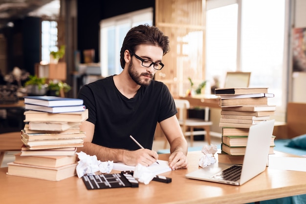 Freelancer bearded man taking notes sitting at desk.