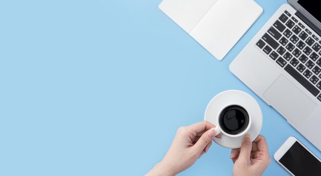 フリーランサーのブログライターの女性が自宅でコーヒーの仕事できれいな水色の机の上でリラックスするために飲むコンセプトコピースペースフラットレイトップビューモックアップ