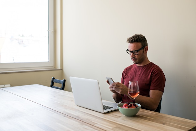 Freelancer die laptop en mobiele telefoon thuis gebruikt