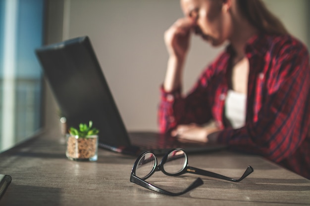 Freelancer die oogvermoeidheid voelt na een lange dag werken en een laptop gebruiken.