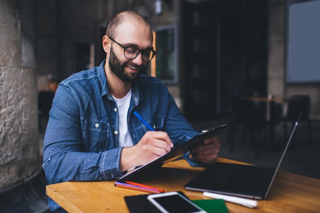 Foto freelancer document schrijven en laptop gebruiken in café