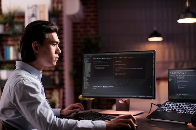 Инженер-фрилансер кодирует программу брандмауэра на мониторе и ноутбуке, используя сервер шифрования для создания сценария сети безопасности с двоичным кодом. Разработка приложения на текстовом интерфейсе данных, его программирование.