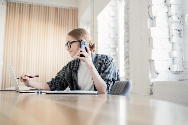 A freelancer in a formal suit a woman with glasses works with documents and uses a laptop