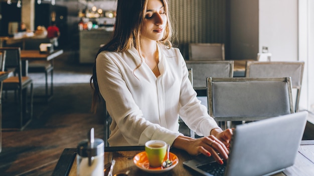 Freelancer lifestyle. Online job. Relaxed business woman working on laptop in coffee shop.