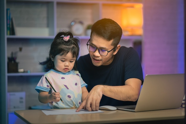 Freelancer man working with laptop on the table and talking with his daughter