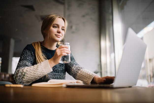 Freelancer met behulp van laptop, typen op toetsenbord, koffie drinken op kantoor