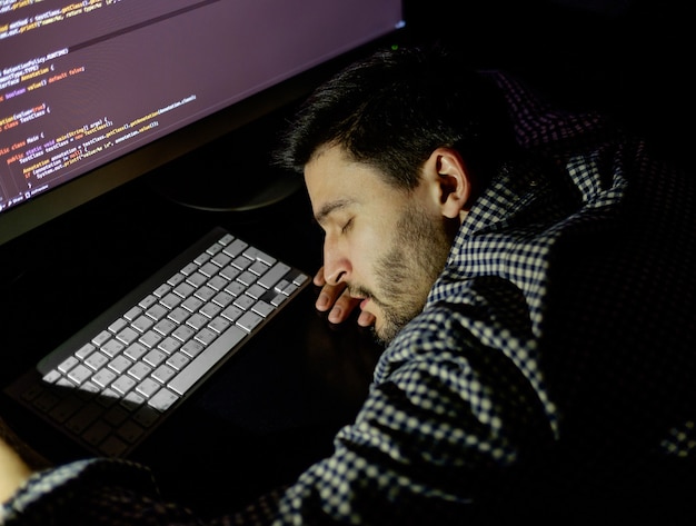 Freelancer programmer falling his face down taking a nap with computer. Concept of tired and lazy