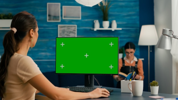 Freelancer searching the internet on green screen chroma key display using web advertisiment in chromakey PC. Home office computer with mockup