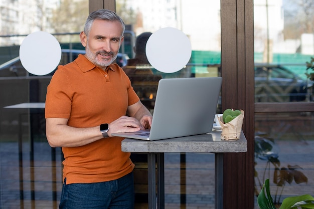 Freelancer-shirt werkt online op de laptop in het straatcafé