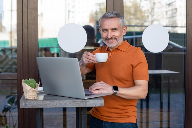 Freelancer-shirt werkt online op de laptop in het straatcafé