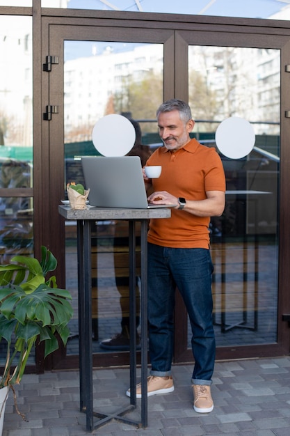 Freelancer-shirt werkt online op de laptop in het straatcafé