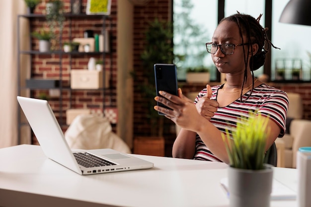 Libero professionista che mostra un gesto di apprezzamento sulla videochiamata dello smartphone, donna che lavora da casa. dipendente con il pollice in su che partecipa a una riunione virtuale, lavoratore remoto che chatta in teleconferenza