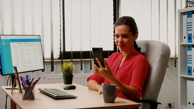 Freelancer talking with colleague using phone webcam in modern office. Entrepreneur working with business remotely team discussing chatting having online conference, webinar with internet technology