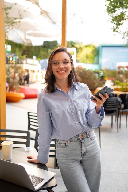 写真 屋外カフェに座っているスマートフォンとラップトップを使用するフリーランサー