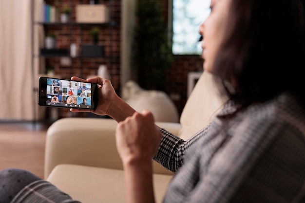 Freelancer using smartphone with online videocall conference to talk to colleagues on webcam. Chatting on remote teleconference meeting with mobile phone app, internet videoconference.