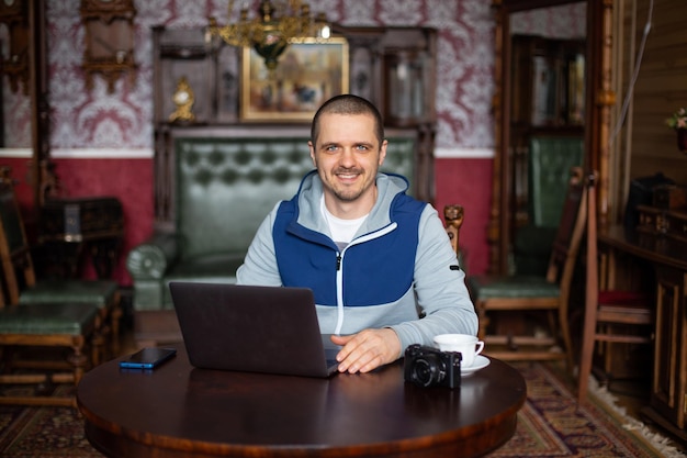 Freelancer or vlogger man with laptop on desk looking and smiling at camera