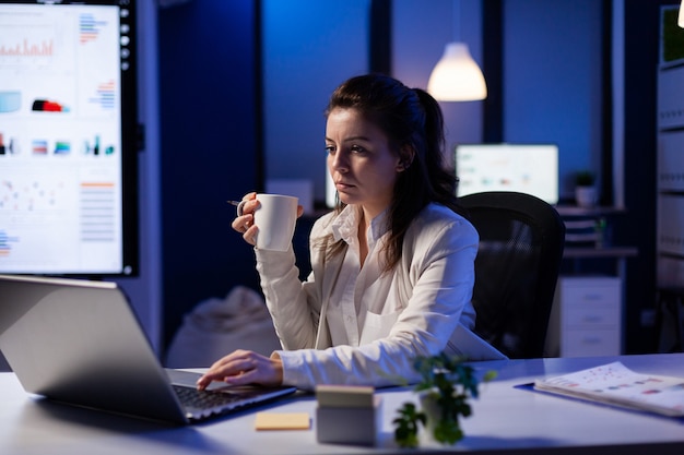Freelancer vrouw met een kopje koffie tikken op zakelijke computer overbelasting bij marketing project
