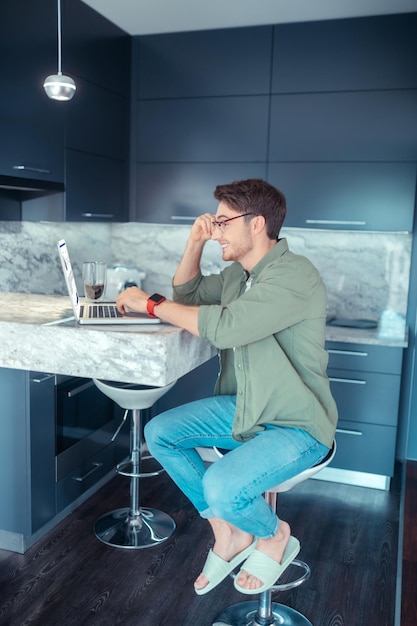 Freelancer wearing glasses working on laptop sitting in the kitchen