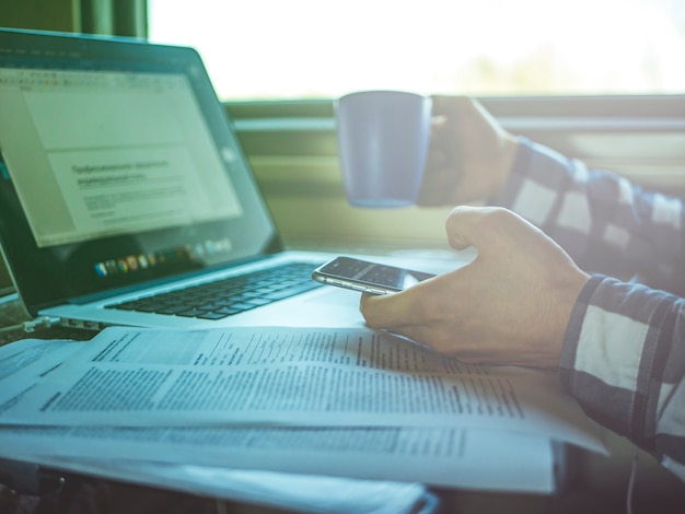 Freelancer werkt met laptop en papier in de trein bij het raam