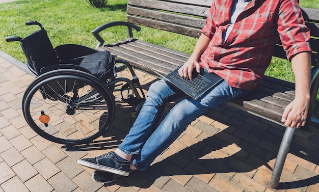Фрилансер с ограниченными физическими возможностями в инвалидной коляске, работающий в парке