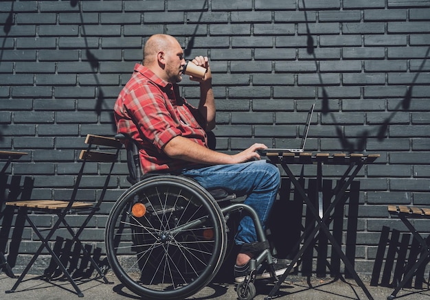 Photo freelancer with a physical disability who uses wheelchair working at the street cafe