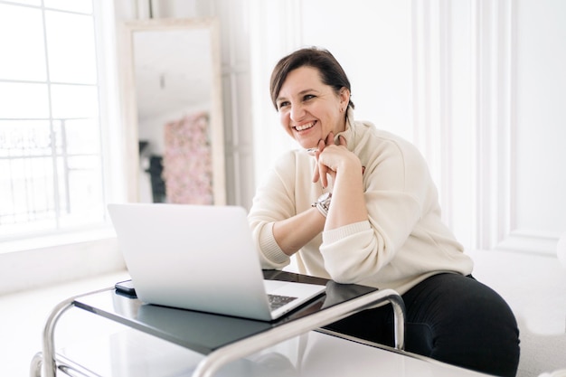 A freelancer woman smiles at the office using a laptop online video communication chatting