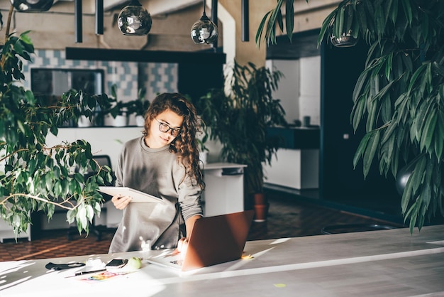 Foto donna freelance che usa il portatile in un comodo ufficio verde in un luogo di lavoro moderno