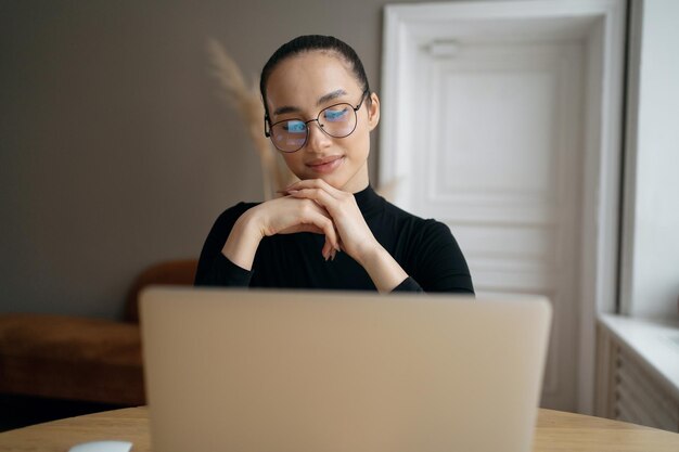 Freelancer a woman with glasses uses a laptop in a modern office writes a message to the mail