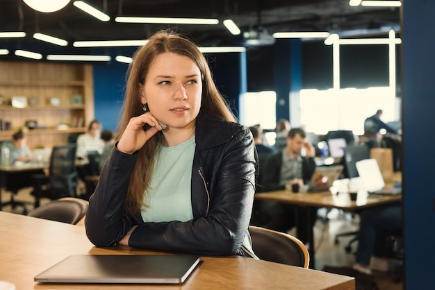 Photo freelancer woman working at co-working or creative space, sitting near laptop over group of people