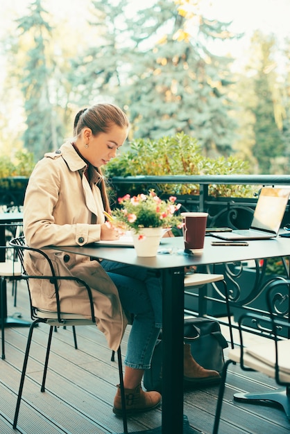 Freelancer woman working from remote, woman sitting in cafe and writing in planner