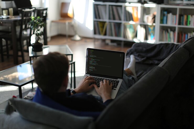 Photo freelancer working from home writing code on sofa