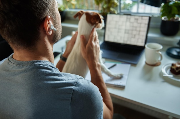 Фрилансер, работающий в домашнем офисе с женщиной-собакой, использующей ноутбук и пишущей в блокноте, сидя за столом
