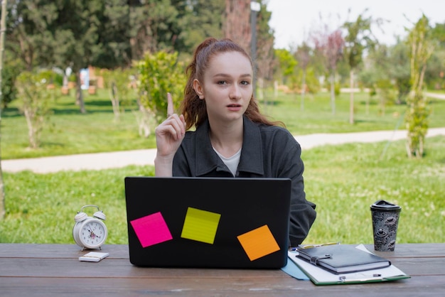 Photo freelancer working outdoors showing up pointing by finger looking