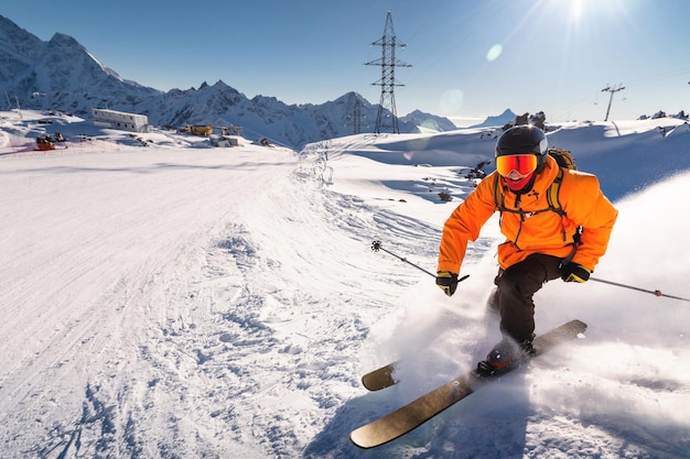 Freerider in een helder pak is skiën met grote splashes van sneeuw op een zonnige dag jonge skiër grote