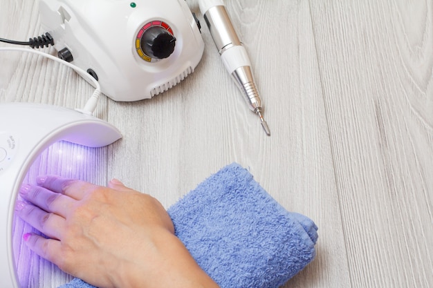 Frees en led UV-lamp drogen vrouw nagel op grijze houten achtergrond. Een set cosmetische hulpmiddelen voor professionele hardware-manicure. Bovenaanzicht