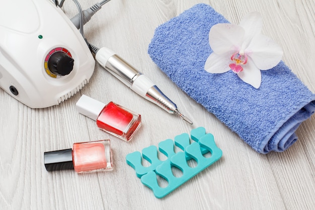 Frees, nagellakken, teenscheiders en handdoek op grijze houten ondergrond. Een set cosmetische hulpmiddelen voor professionele hardware-manicure. Bovenaanzicht.