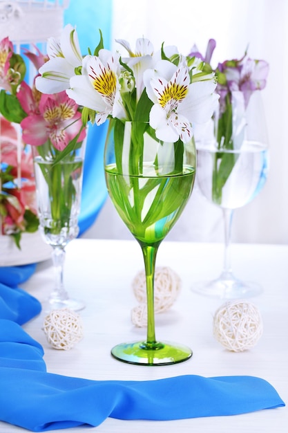 Freesias in glasses on table on fabric background