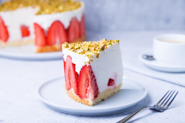 Freesier cake with fresh strawberries and pistachios. French classic dessert. Portion of cake on a white plate close-up.