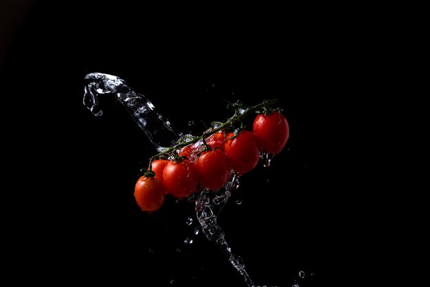 Freeze motion. Cherry tomatoes on black background with splashing water